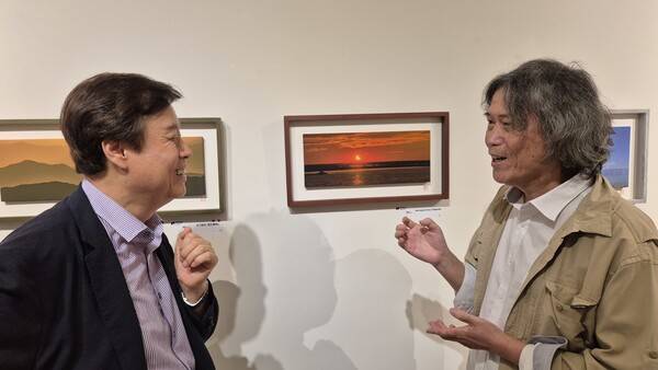 이지상(오른쪽) 작가가 사진전을 찾은 도종환 시인에게 자신의 작품 ‘아무르강의 일몰’에 관해 이야기하고 있다. 오윤주 기자