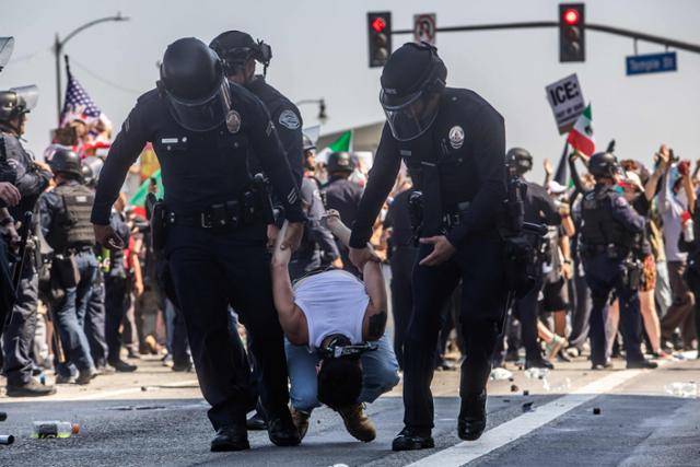 8일 미국 캘리포니아주 로스앤젤레스(LA)에서 LA 경찰이 LA 연방청사 앞에서 도널드 트럼프 행정부의 고강도 이민자 단속에 반발하는 시위 참가자를 체포하고 있다. 로스앤젤레스=AFP 연합뉴스