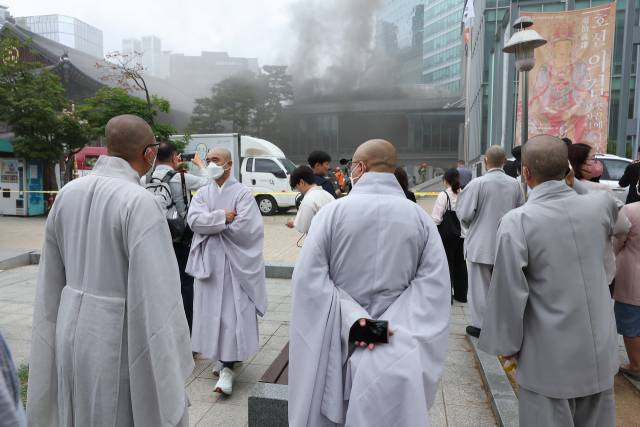 10일 서울 종로구 조계사 옆 한국불교역사문화기념관 국제회의장에서 화재가 발생한 가운데 스님들이 현장을 바라보고 있다. 연합뉴스