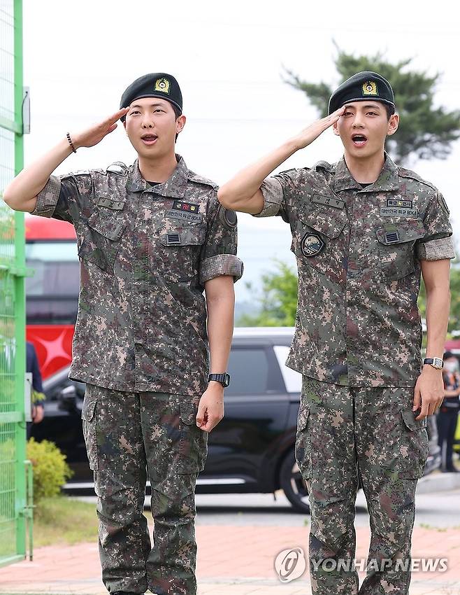 육군 현역 복무를 마치고 만기 전역한 그룹 방탄소년단(BTS) RM과 뷔가 10일 강원 춘천시 신북읍체육공원에서 취재진을 향해 거수경례하고 있다.