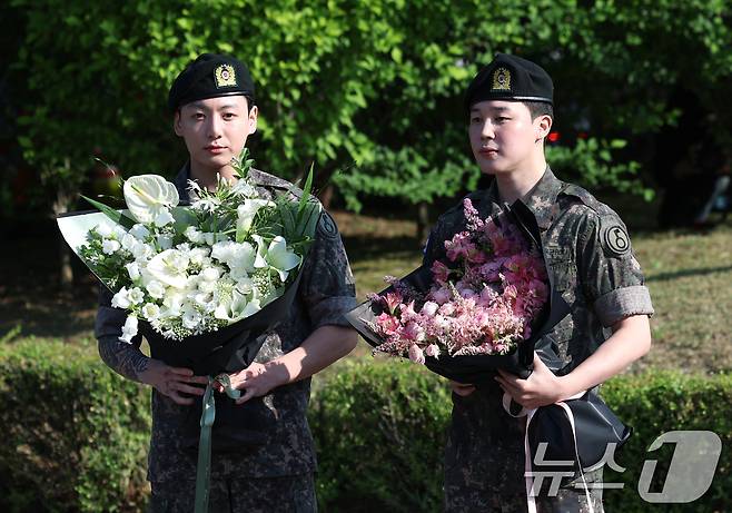 방탄소년단(BTS)의 정국과 지민(오른쪽)이 11일 오전 경기도 연천군 연천공설운동장에서 군 복무를 마친 뒤 전역 인사를 하고 있다. ⓒ News1 권현진 기자