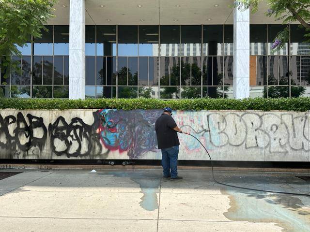 9일 미국 캘리포니아주 로스앤젤레스 시빅센터 앞에서 한 남성이 전날 시위대가 외벽에 새긴 낙서를 지우고 있다. 로스앤젤레스=이서희 특파원