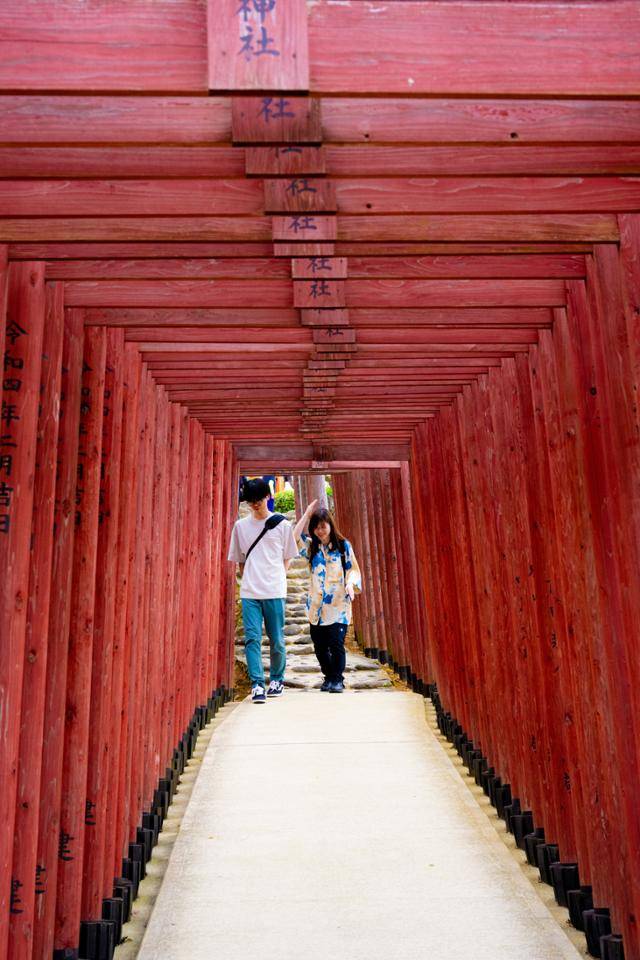 일본 규슈 사가현 유토쿠이나리 신사의 토리이 사이로 사람들이 걷고 있다.