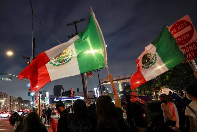 불법 이민자 단속 정책에 반발한 LA 시위대가 멕시코 국기를 들고 있다. 사진=REUTERS