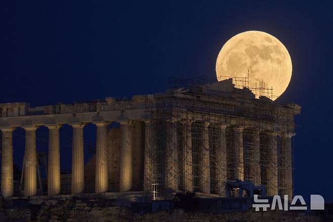 [아크로폴리스=AP/뉴시스] 10일(현지 시간) 아테네 아크로폴리스 파르테논 신전 뒤로 스트로베리 문이 떠오르고 있다. 스트로베리 문은 북미 원주들이 딸기를 수확하는 시기인 6월에 뜨는 달을 의미한다. 2025.06.11.