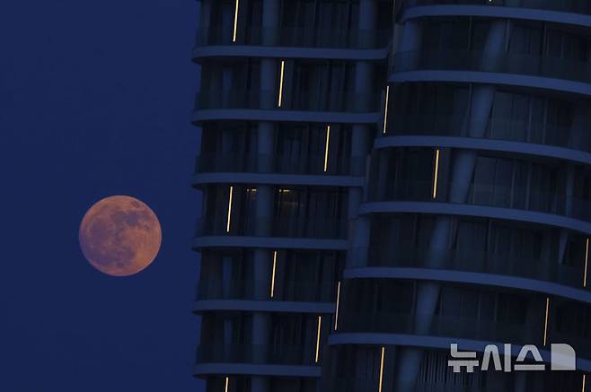 [키프로스=AP/뉴시스] 10일(현지 시간) 지중해 동부 키프로스 섬의 아이아 나파의 한 건물 뒤에 스트로베리 문이 떠있다. 스트로베리 문은 북미 원주들이 딸기를 수확하는 시기인 6월에 뜨는 달을 의미한다. 2025.06.11.<font style="vertical-align: inherit;"><font style="vertical-align: inherit;"></font></font>