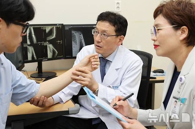[서울=뉴시스][서울=뉴시스]전인호 서울아산병원 정형외과 교수(가운데)가 환자가 직접 평가하는 통증 정도를 확인하며 환자 건강상태 자가평가(PROMs)를 진행하고 있다. (사진= 서울아산병원 제공) 2025.06.11. photo@newsis.com.