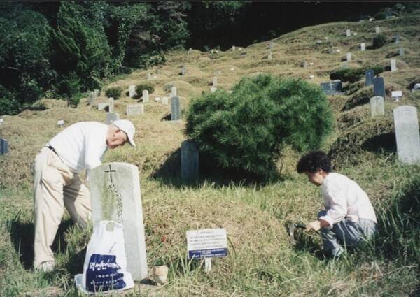 고인이 생전 돌보던 장애인의 묘지를 찾아 벌초하고 있다. 필자 제공