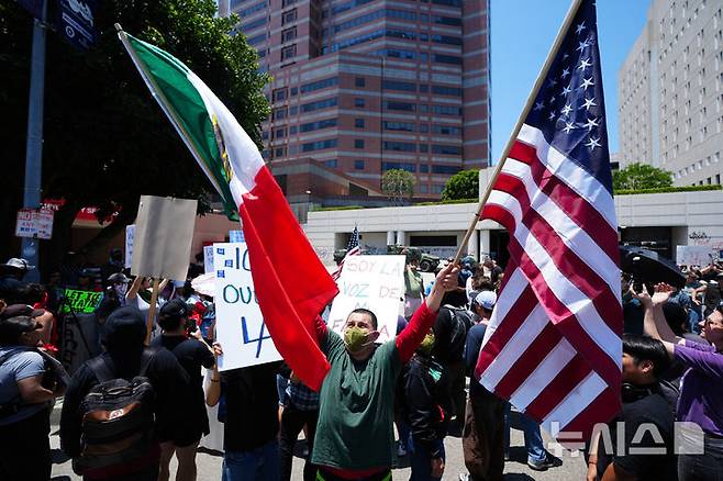 [로스앤젤레스=AP/뉴시스] 10일(현지 시간) 미 캘리포니아주 로스앤젤레스에서 성조기와 멕시코 국기를 든 시위대가 이민세관단속국(ICE)의 불법 이민자 단속을 규탄하고 있다. 2025.06.11.
