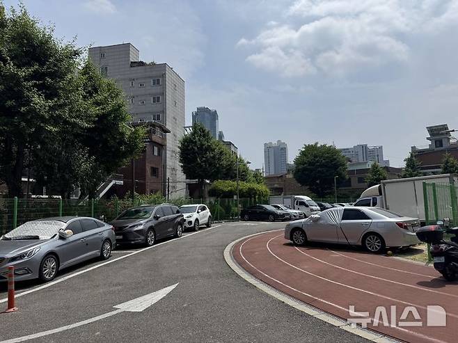 [서울=뉴시스]]김지윤 인턴기자 = 서울 광진구 화양초등학교 전경. 2023년 폐교된 이후 2년째 방치 중인 이 부지는 현재 임시 주차장으로 활용되고 있다. 사진은 화양초 운동장 한편에 차량 수대가 주차돼 있는 모습. 2025.06.12