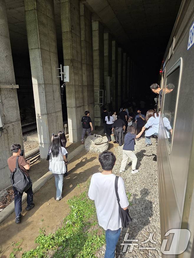 13일 오전 경의중앙선 신촌역 인근에서 사다리차 전도사고가 발생해 가좌역~신촌역 구간이 양방향 통제된 가운데 서울역행 경의중앙선 열차에 탑승한 승객들이 열차에서 내려 선로를 따라 대피하고 있다. (독자 제공, 재판매 및 DB금지)