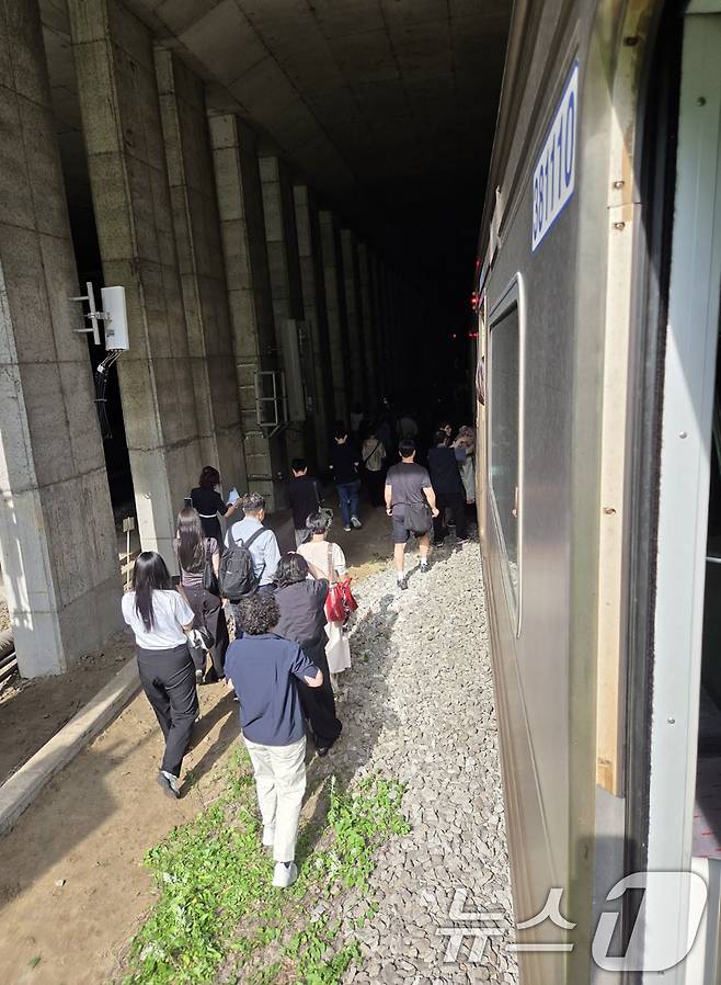13일 오전 경의중앙선 신촌역 인근에서 사다리차 전도사고가 발생해 가좌역~신촌역 구간이 양방향 통제된 가운데 서울역행 경의중앙선 열차에 탑승한 승객들이 열차에서 내려 선로를 따라 대피하고 있다. (독자 제공, 재판매 및 DB금지)