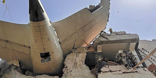 [인도의 비극… 240여 명 탄 런던행 여객기, 이륙 1분 만에 추락] 의과대학 기숙사 덮쳐 - 12일 오후 인도 서부 구자라트주 아메다바드의 공항에서 이륙 직후 추락한 에어인디아 여객기(편명 AI171)의 꼬리날개 부분이 부서진 건물 잔해에 걸쳐 있다. 현지 언론은 "여객기가 인근 의과대학 기숙사 건물에 충돌해 학생 다수가 숨졌다"고 보도했다. 여객기에는 승객·승무원 등 총 240여 명이 탑승했던 것으로 전해졌다. /AFP 연합뉴스