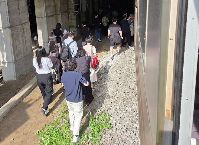 13일 오전 경의중앙선 신촌역 인근에서 사다리차 전도사고가 발생해 가좌역~신촌역 구간이 양방향 통제된 가운데 서울역행 경의중앙선 열차에 탑승한 승객들이 열차에서 내려 선로를 따라 대피하고 있다. /뉴스1