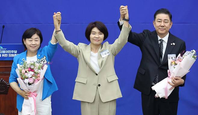 13일 더불어민주당 원내대표로 선출된 김병기 의원이 선거관리위원장을 맡은 한정애 의원, 원내대표를 두고 경쟁했던 서영교 의원(오른쪽부터)과 함께 손을 들어 올리고 있다. 한주형 기자