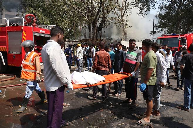 12일(현지시간) 인도 아메다바드에서 추락한 에어인디아 여객기 현장에서 구조대원들이 들것을 이용해 희생자를 수습하고 있다. [UP]