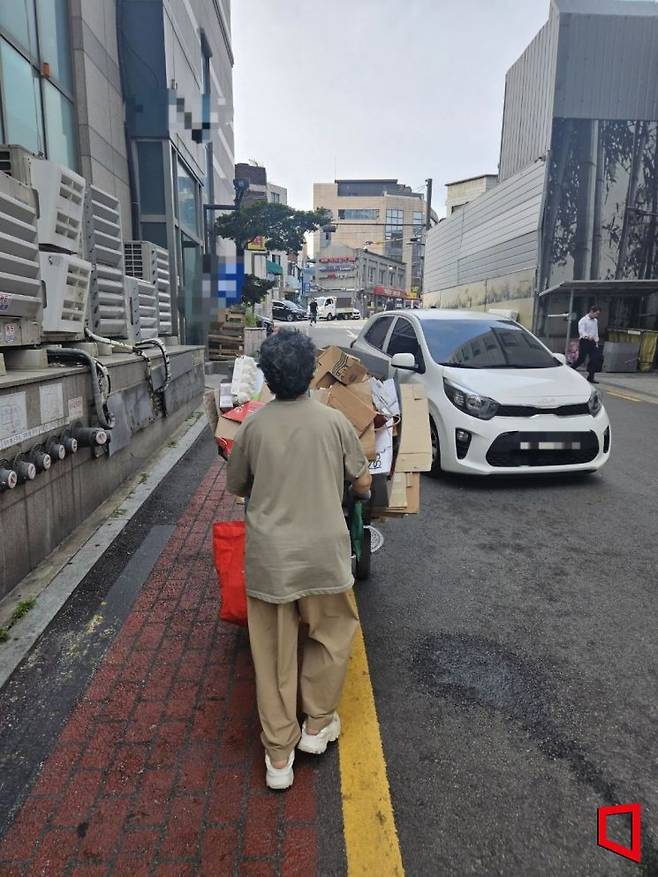 지난 10일 오전 서울 중구 신당동에서 한 노인이 페지를 실은 수레를 끌고 가고 있다. 마주 오던 차량이 수레를 피해 운행하는 모습이 눈에 띈다. 박승욱 기자