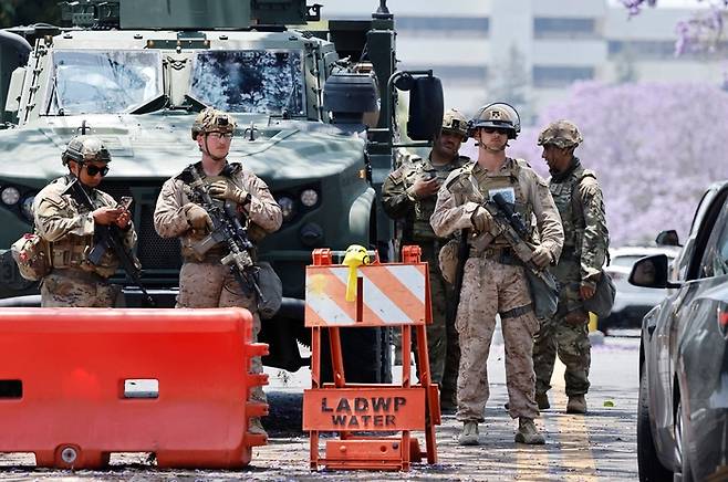 13일(현지시간) 미국 로스앤젤레스(LA)에서 해병대원과 주방위군이  LA 윌셔 연방청사를 경계하는 임무를 수행하고 있다. [사진 출처 = AFP, 연합뉴스]