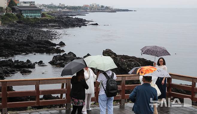 [제주=뉴시스] 우장호 기자 = 올해 첫 장맛비가 내리는 12일 오후 제주 도내 대표적인 관광지 용두암을 찾은 내·외국인 방문객이 우산을 쓴 채 관광 일정을 소화하고 있다. 2025.06.12. woo1223@newsis.com