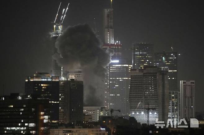[텔아비브=AP/뉴시스] 14일(현지 시간) 이스라엘 텔아비브의 한 건물이 발사체의 타격을 받아 연기가 치솟고 있다. 이란은 13일 밤과 14일 새벽 탄도미사일 등을 동원해 이스라엘 예루살렘과 텔아비브를 공격했다. 2025.06.14.