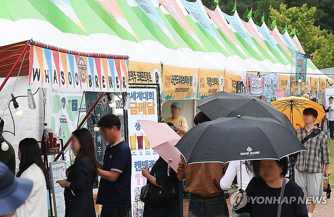 비 오는 날 즐기는 '대구 수제맥주 페스티벌' (대구=연합뉴스) 윤관식 기자 = 13일 대구 수성구 수성못 상화동산에서 개막한 '대구 수제맥주 페스티벌'에서 시민들이 수제맥주 부스를 살펴보고 있다. 2025.6.13 psik@yna.co.kr