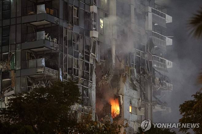 건물 피해 (텔아비브 AFP=연합뉴스) 13일(현지시간) 밤 이스라엘 중심도시 텔아비브의 한 건물이 이란 미사일에 맞아 불이 났다. photo@yna.co.kr