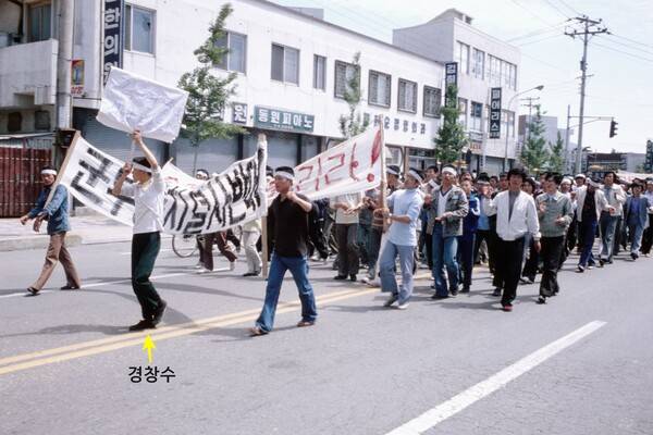 1980년 5월 사진. 맨 앞에 하얀 머리띠를 두르고 피켓을 들고 있는 소년이 경창수씨다. (강연 자료를 재촬영한 사진으로, 사진 원본은 저널리스트 노먼 소프가 촬영한 것이다.)