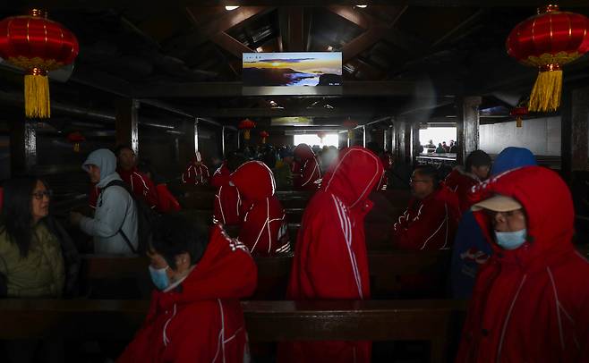 지난 11일 백두산 정상(북파)은 비바람과 안개로 천지를 목격할 수 없었다. 이날 기온은 7도 정도였지만, 강하게 부는 비바람에 체감온도는 영하권에 가까울 정도였다. 대부분의 관광객들은 두꺼운 패딩을 입었다. 사진은 북파 정상에 올랐지만, 안개 등으로 천지를 보지 못한 관광객들이 실망한 채 하산하는 모습. 사진 중간에는 해가 뜬 백두산의 사진이 걸려있다. /박성원 기자