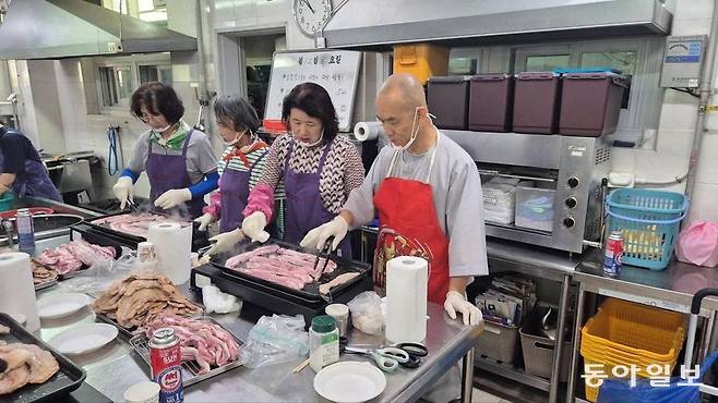 12일 광주 남구 방림2동에 있는 무료급식소 ‘성요셉의 집 사랑의 식당’에서 문빈정사 법공 주지스님과 신도들이 삼겹살을 구워 어르신들에게 점심을 대접하고 있다. 사랑의 식당 제공