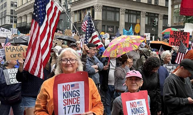 미국 뉴욕 맨해튼 거리에서 열린 \'\'노 킹스\'\' 집회에서 참가자들이 피켓을 들고 행진하고 있다. 연합뉴스