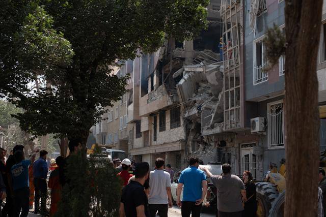 이란인들이 14일 수도 테헤란에서 이스라엘군 공습으로 무너진 건물을 살펴보고 있다. 테헤란=UPI 연합뉴스