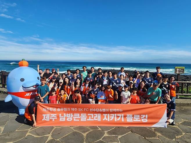 제주항공 에코머 승무원들과 제주SK FC 선수들, 팬들이 지난 14일 제주도 서귀포시 논짓물 해변에서 제주 남방큰돌고래 보호를 위한 해양정화활동 진행 후 기념 촬영을 하고 있다. [제주항공 제공]