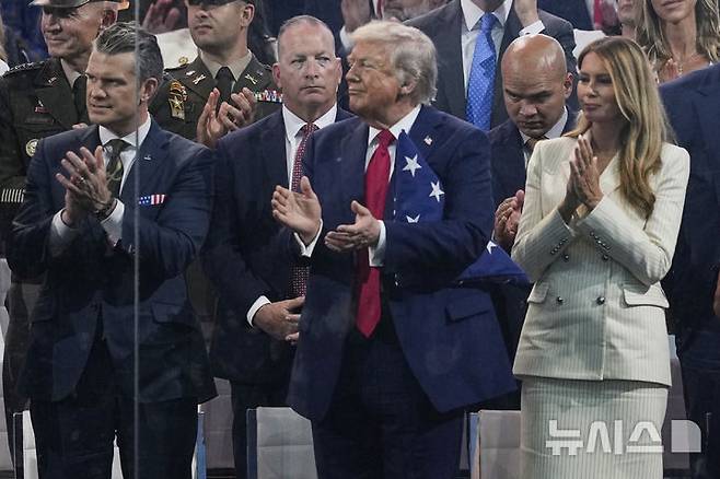 [워싱턴=AP/뉴시스]도널드 트럼프 미국 대통령이 부인인 멜라니아 여사와 14일(현지 시간) 미국 워싱턴DC에서 열린 미 육군 250주년 군사 퍼레이드를 지켜보며 박수치고 있다. 2025.06.15.