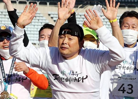 ‘국민 마라토너’ 이봉주가 28일 경기도 부천시 부천종합운동장에서 열린 ‘이봉주 쾌유 기원 마라톤’에서 목표 코스를 완주, 피니시 라인을 통과하고 있다. 이봉주는 근육긴장 이상증을 앓아 수술받았지만 걸을 때 허리를 펼 수 없는 상태다. 2021.11.28.연합뉴스