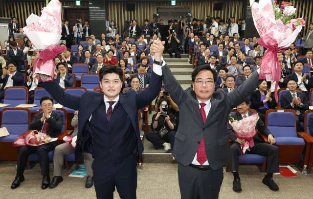 국민의힘 신임 원내대표로 당선된 송언석 의원(오른쪽)이 16일 원내대표 선출 의원총회가 열린 서울 여의도 국회 회의장에서 김용태 비상대책위원장과 손을 잡고 기념촬영하고 있다. 연합뉴스