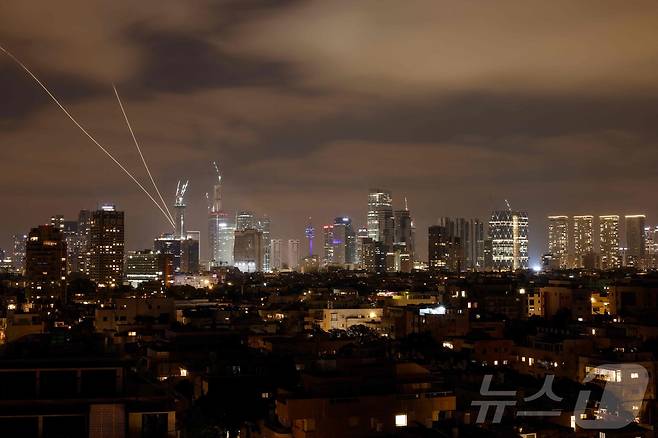 2025년 6월 15일, 이란의 로켓이 이스라엘 텔아비브 상공에서 발사된 가운데 이스라엘 방공 시스템이 가동되어 이란의 미사일을 요격하고 있다.  ⓒ AFP=뉴스1