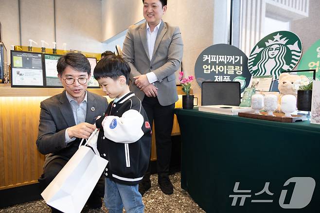 김완섭 환경부장관이 충북 청주시 소재 스타벅스 청주 분평(DT)점에서 스타벅스·청주시와 함께 ‘맞춤형 일회용 컵 회수․보상을 위한 자발적 협약’을 체결하고, 반납된 일회용컵으로 업싸이클 제작된 인형을 매장 방문 어린이에게 선물하고 있다. (환경부 제공. 재판매 및 DB 금지) 2025.4.10/뉴스1