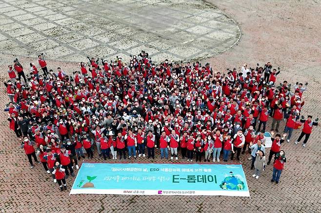 BNK부산은행 직원들이 부산 사상구 삼락생태공원에서 생태교란 식물을 제거하는 봉사활동을 하고 기념사진을 촬영하고 있다. BNK부산은행 제공