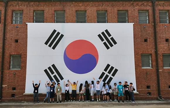 서대문형무소에 걸린 태극기를 배경으로 학생들이 기념사진을 촬영하고 있다 [사진=달성군]