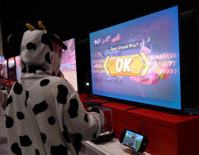 An attendee wearing a cow costume while playing Mario Kart World by Nintendo Switch 2 during the Nintendo Switch 2 Experience at the ExCeL London international exhibition and convention centre in London, Britain, April 11, 2025. [REUTERS/YONHAP]