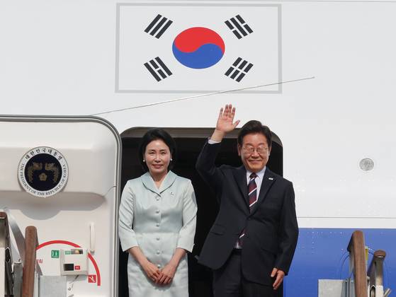 President Lee Jae-myung, right, and first lady Kim Hye-kyung greet onlookers at Seoul Air Base in Seongnam, Gyeonggi, before boarding the presidential jet bound for Canada on June 16. [YONHAP]