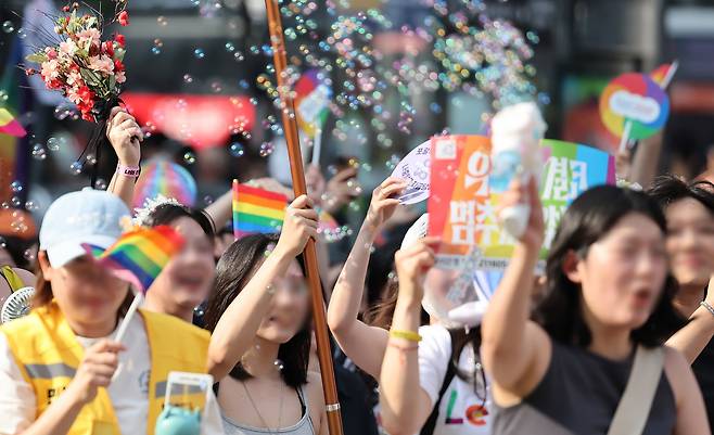 Attendees at the Seoul Queer Culture Festival cheer as they march past Myeongdong Cathedral in Jung District, central Seoul, on June 14. Faces have been blurred at the request of the festival's organizing committee. [NEWS1]
