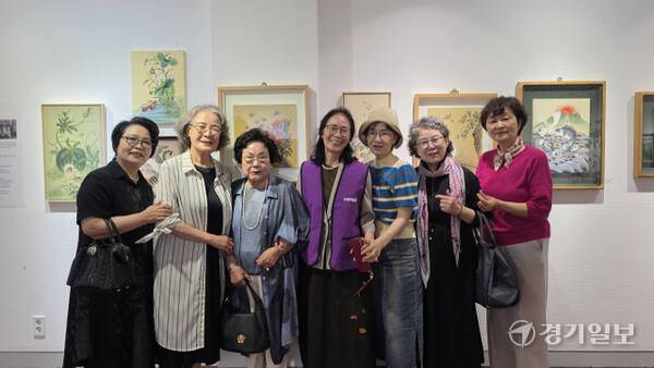 2025 수원시미술단체 아카이브전에 참여한 ‘소망가득’(혜정전통민화작가회) 회원들이 작품 앞에서 기념촬영을 하고 있다. 이나경기자