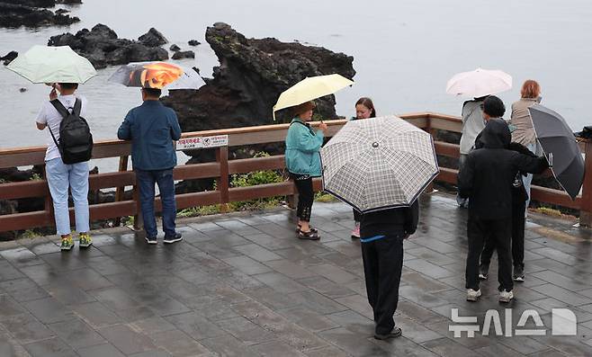 [제주=뉴시스] 우장호 기자 = 지난 12일 오후 제주 도내 대표적인 관광지 용두암을 찾은 내·외국인 방문객이 우산을 쓴 채 관광 일정을 소화하고 있다. 2025.06.12. woo1223@newsis.com