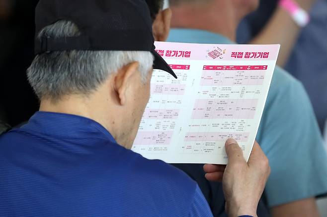 일자리 찾는 노인들. 지난 10일 한 노년층 구직자가 부산의 채용박람회에서 기업 정보를 살펴보고 있다. 뉴스1