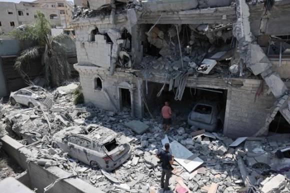 이스라엘 북부 마을 탐라의 주민들이 15일 전날 이란의 미사일 폭격으로 피해를 입은 건물을 살펴보고 있다. AFP 연합뉴스