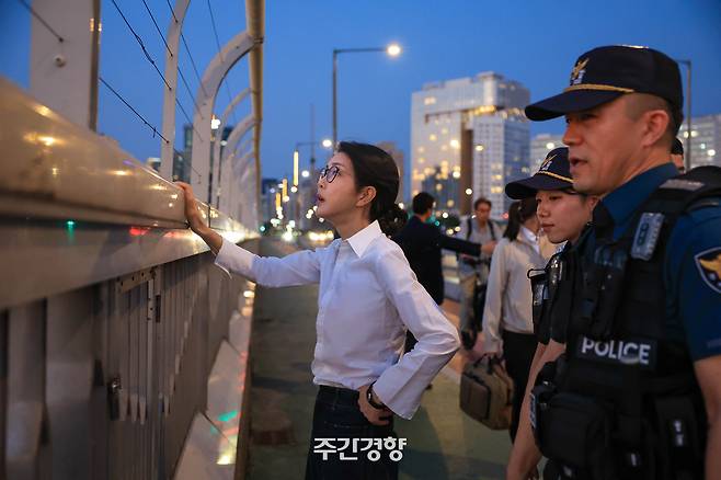 지난해 9월 10일 김건희 여사가 자살 방지를 위해 서울 마포대교 난간에 설치된 도르래를 만져보고 있다. 여사 뒤로 경호 인력이 시민 통행을 막고 있는 모습이 보인다. 대통령실 제공