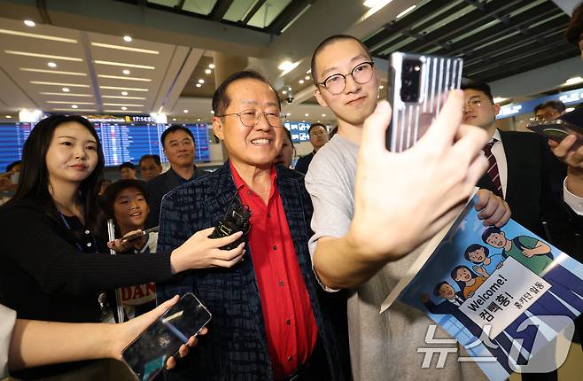 국민의힘 대선 경선에서 탈락한 뒤 정계 은퇴를 선언하고 하와이로 떠났던 홍준표 전 대구시장이 17일 인천국제공항을 통해 귀국해 지지자와 셀카를 찍고 있다. 2025.6.17/뉴스1 ⓒ News1 권현진 기자