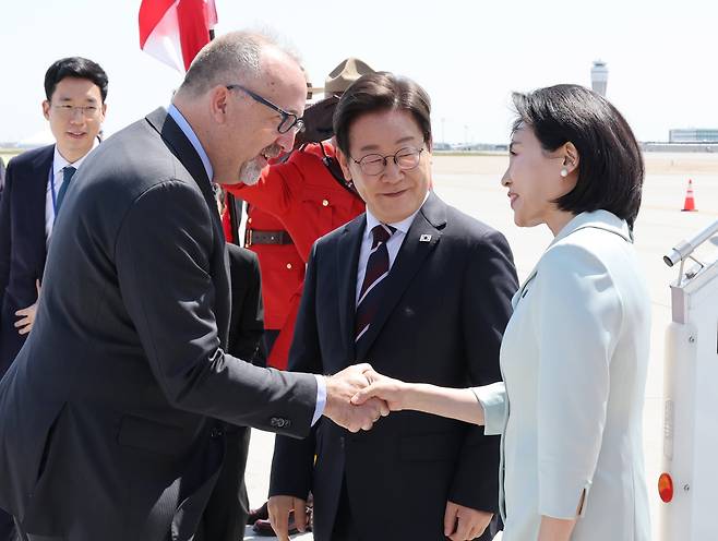 이재명 대통령이 16일(현지 시간) 캐나다 앨버타주 캘거리국제공항에 도착한 가운데 김혜경 여사가 영접 인사와 악수하고 있다./뉴시스