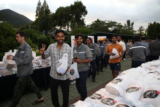 경남 거제시 한화오션 조선소(거제사업장) 외국인 근로자들이 '치킨데이' 때 회사가 나눠준 통닭 1마리와 콜라를 챙겨가고 있다. 사진 한화오션